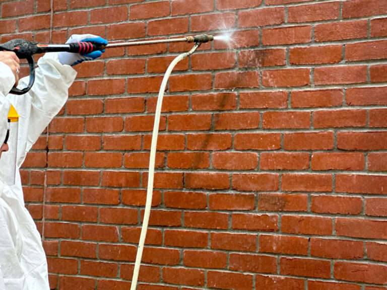 The Clement Construction crew removing graffiti from a brick wall.